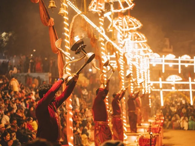 Prêtres levant des lampes cérémonielles allumées pendant l’Aarti du Gange du soir.