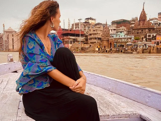 Frau sitzt auf einem Boot und blickt auf die Ghats von Varanasi.