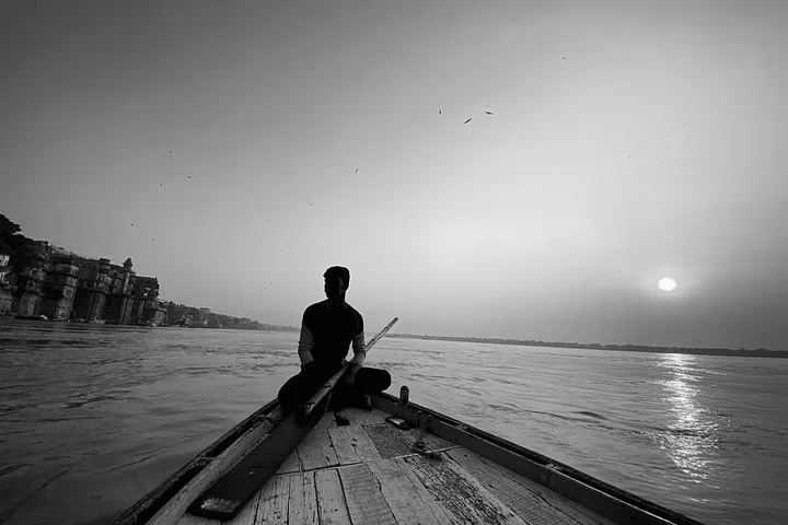 Silhouette of a man rowing a boat on the Ganges River at sunrise.