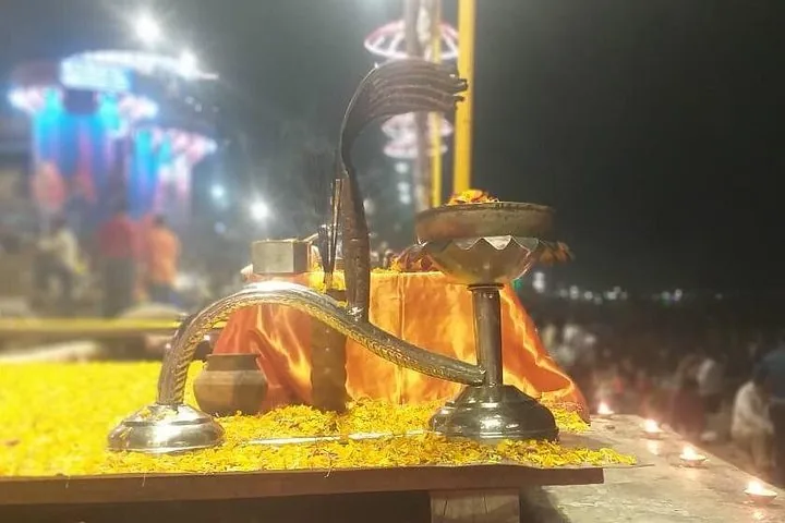 Close-up of a ceremonial lamp with yellow flower petals at the ghat.