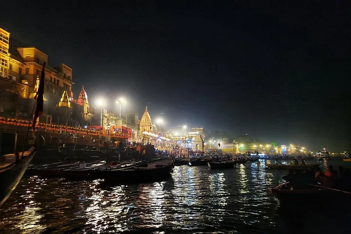 Nachtansicht der beleuchteten Ghats und Boote auf dem Ganges in Varanasi.